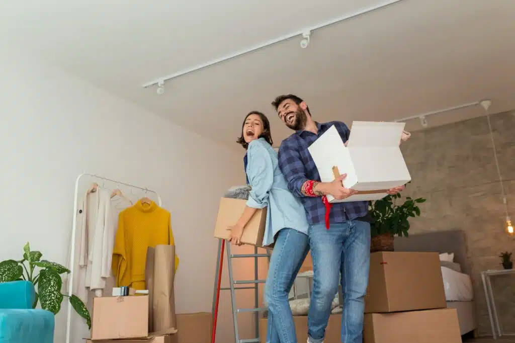 Couple carrying cardboard boxes with their possessions while moving in together