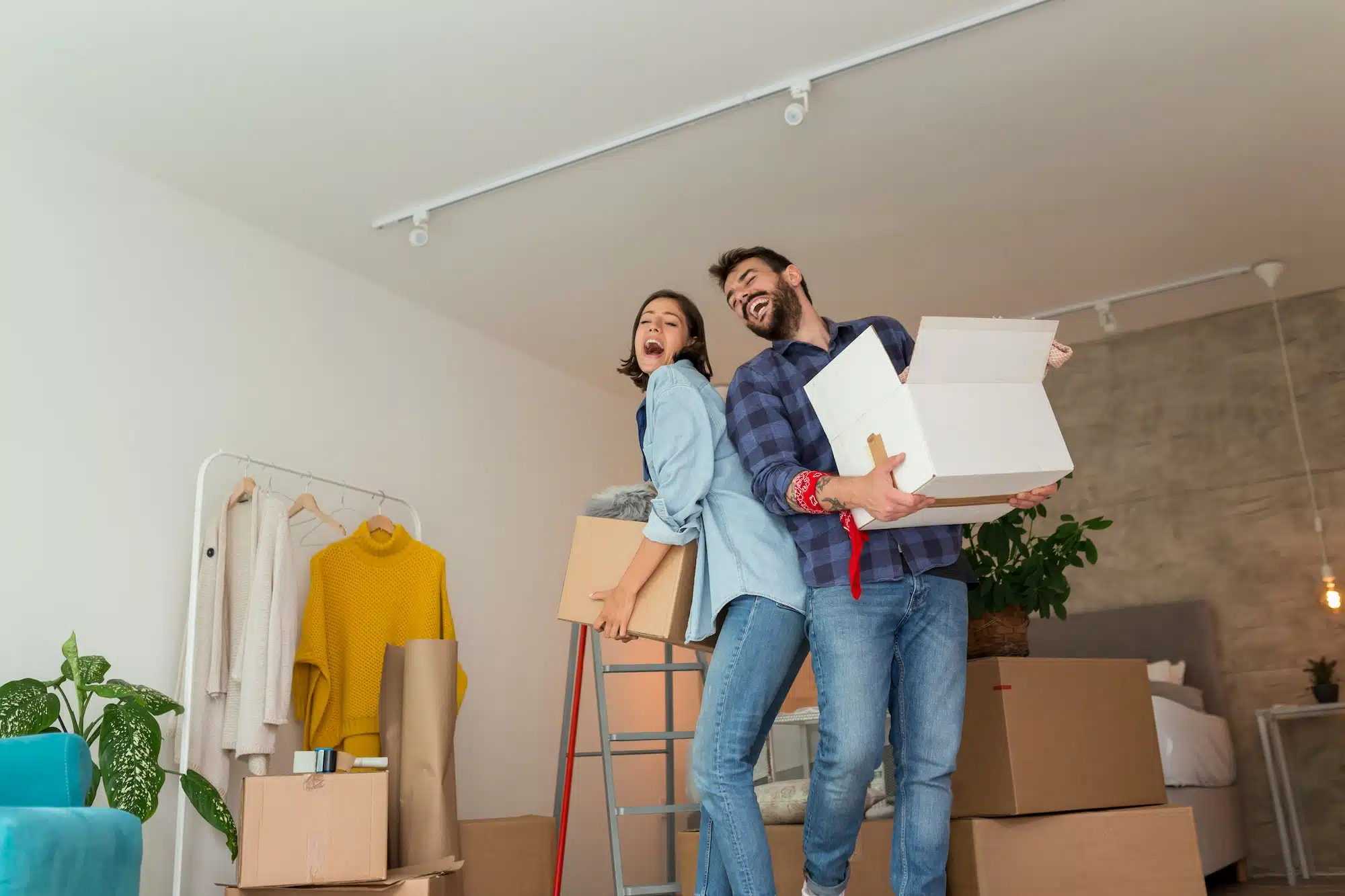Couple carrying cardboard boxes with their possessions while moving in together