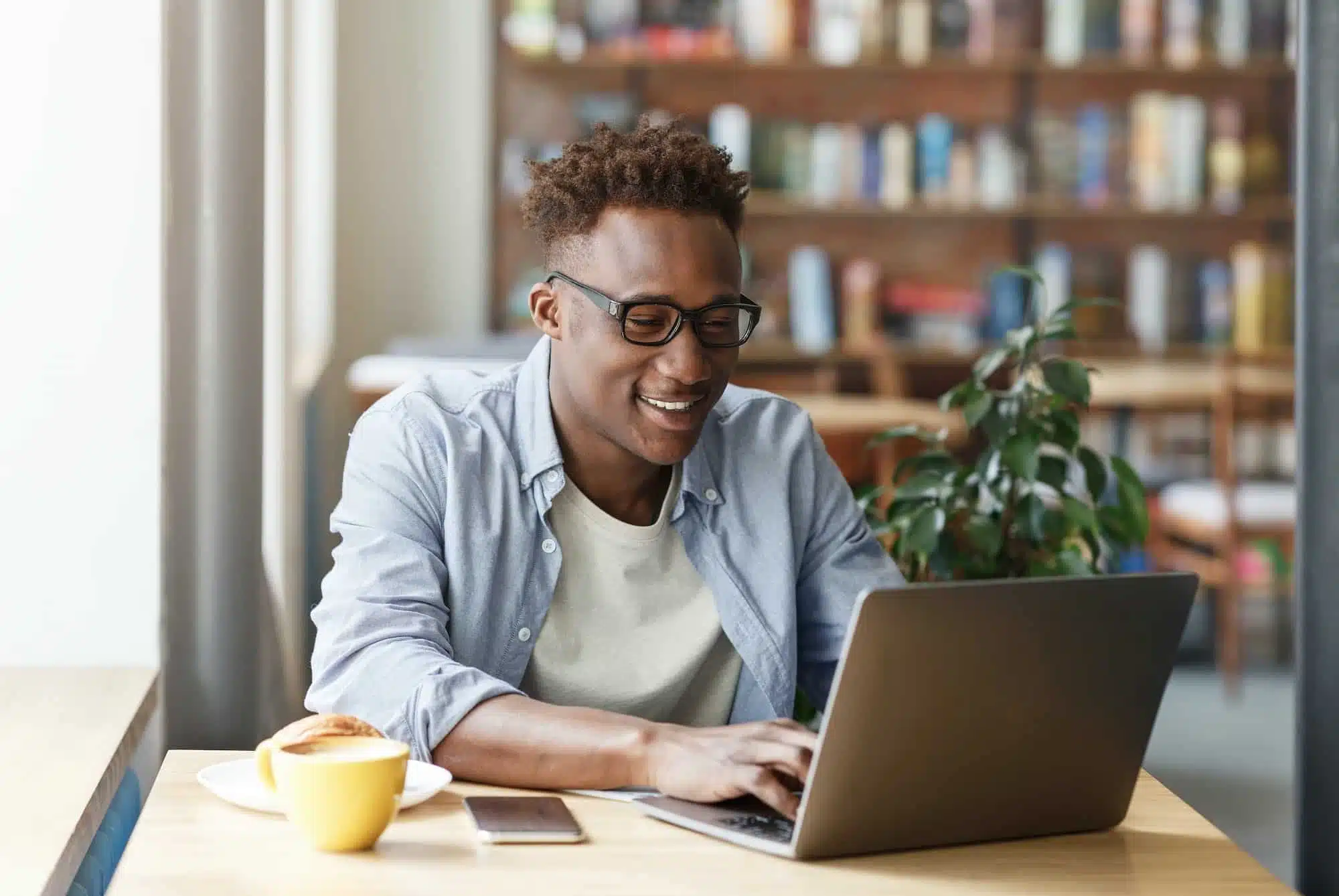 Joyful African American student doing his online homework at urban cafe