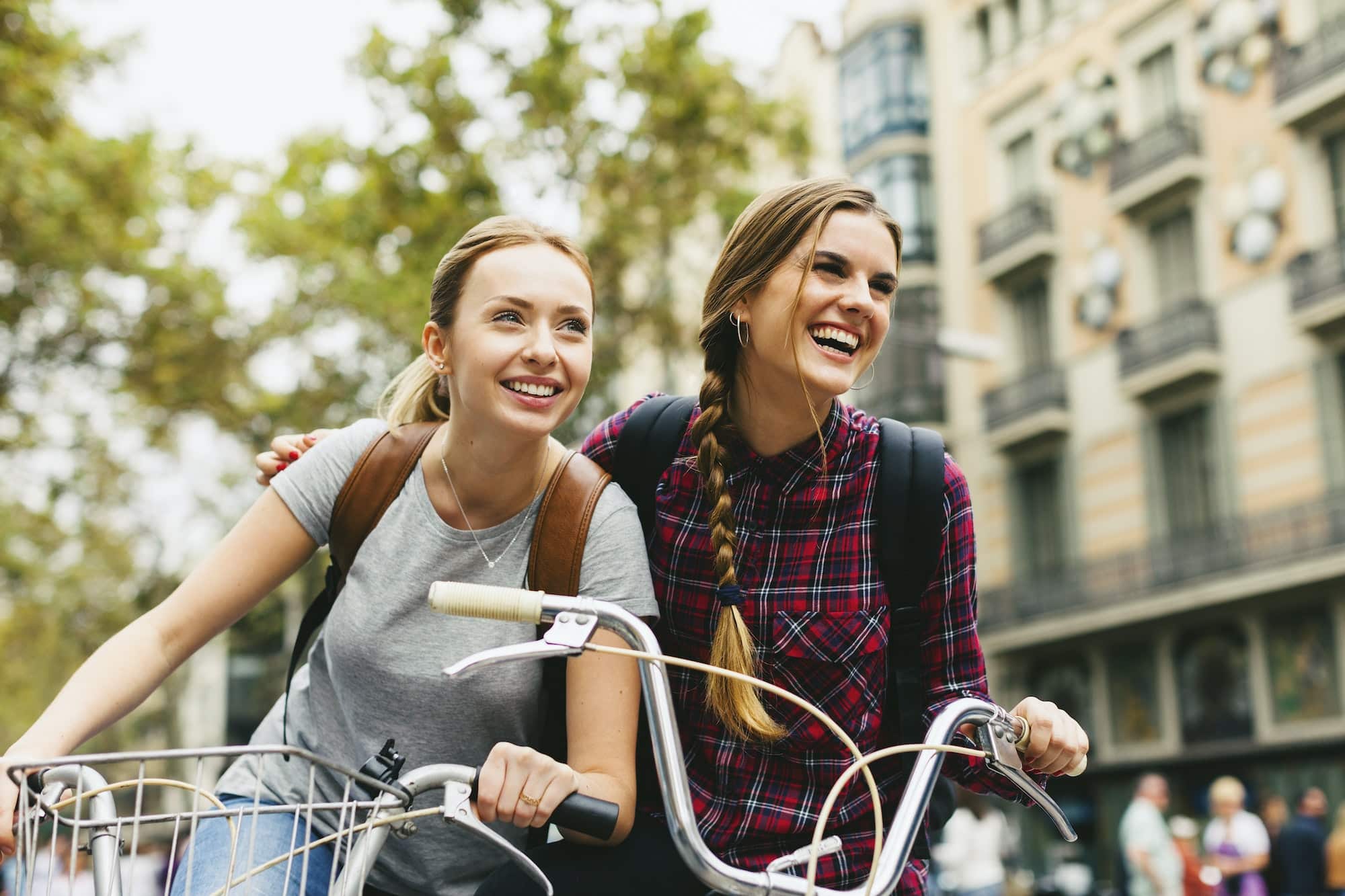 Spain, Barcelona, two young women on bicycles in the city