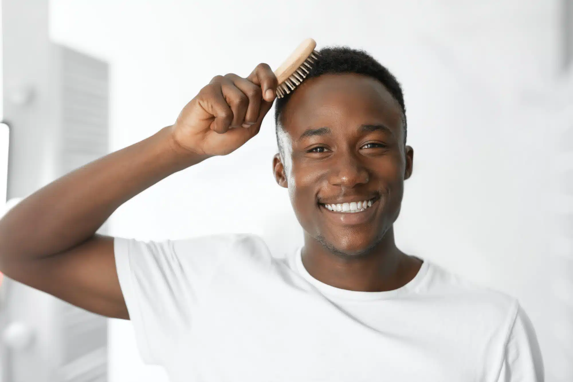 Black Man Combing And Brushing Short Hair In Bathroom Indoors