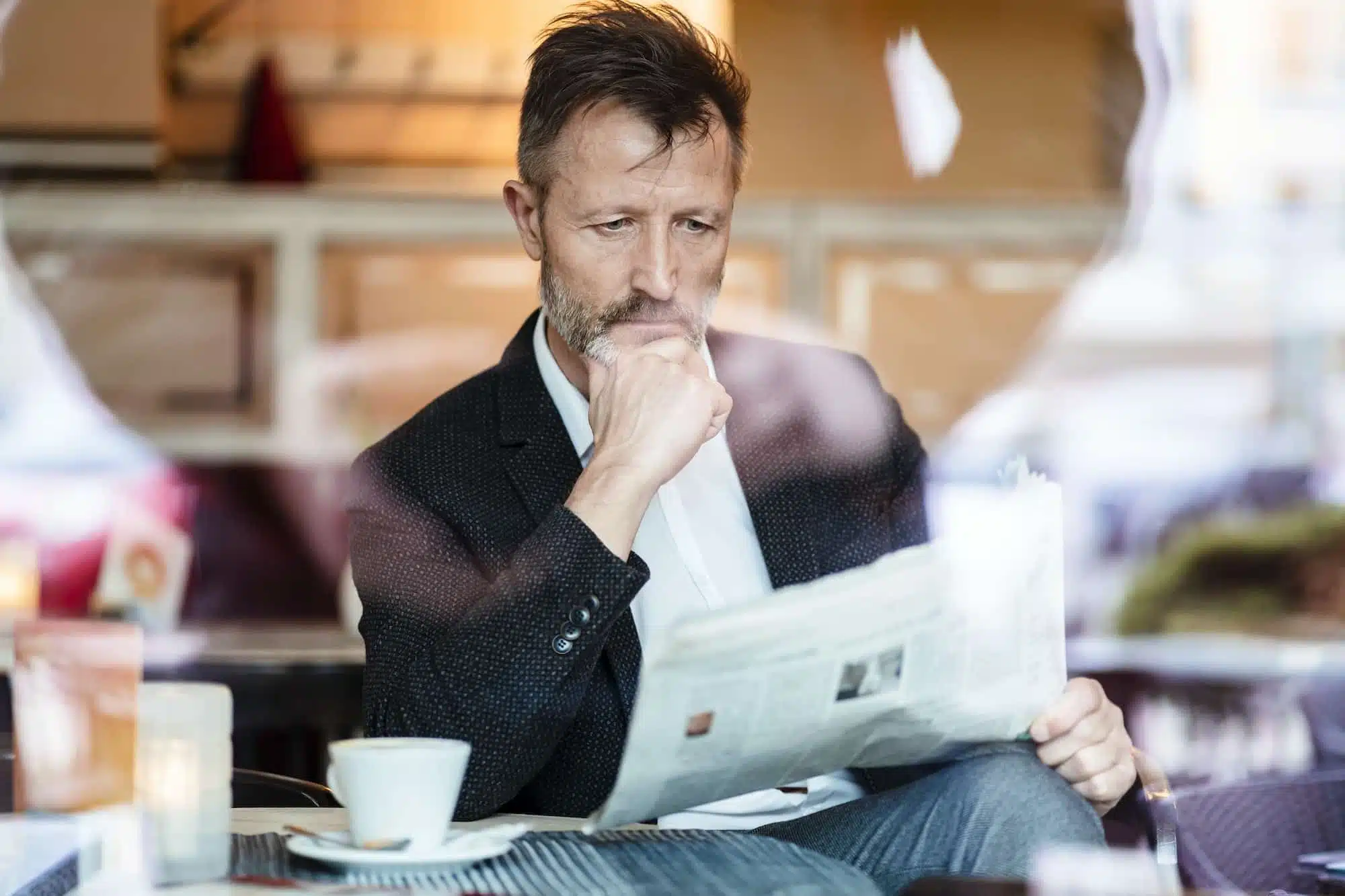 Portrait of pensive mature businessman reading newspaper in a coffee shop