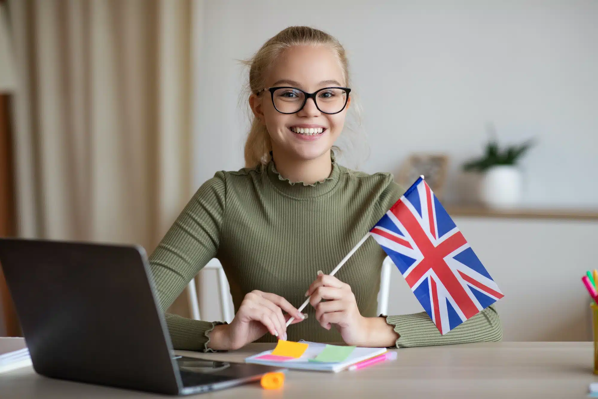Smiling girl with flag of Great Britain using laptop