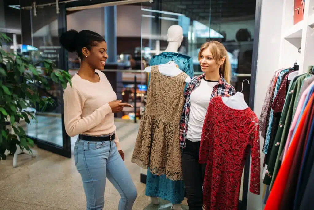 Two female friends choosing dresses, shopping
