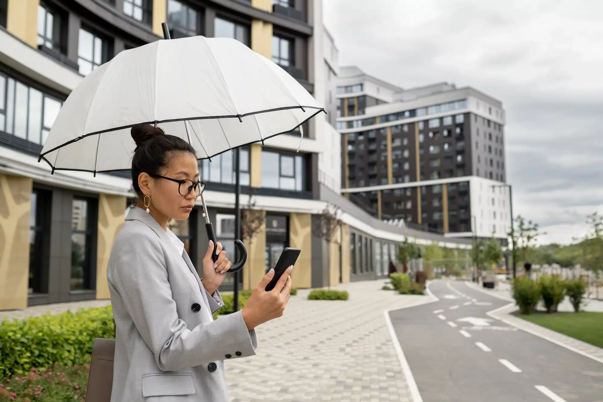 Young elegant businesswoman communicating in video chat in rainy weather