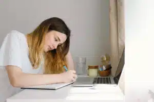 A teenage girl is drawing or doing homework in the bedroom. A teenager studies at home.