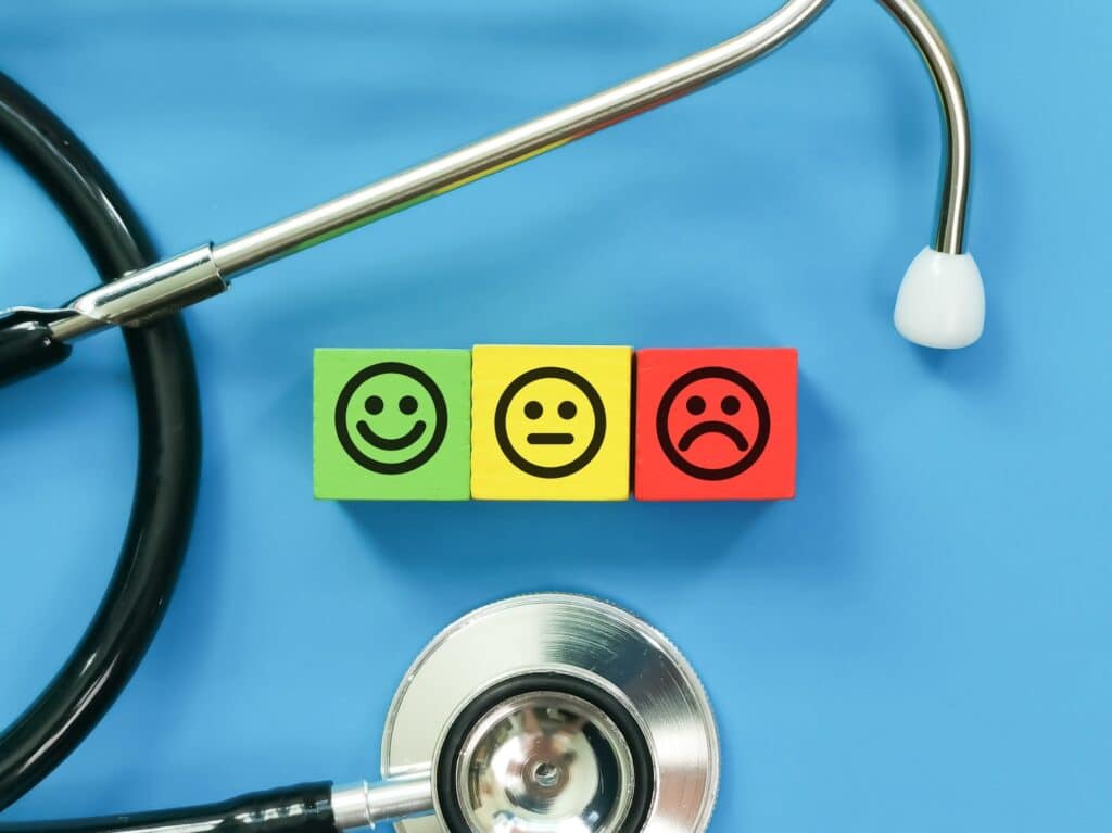 Medical satisfaction survey concept. Emotional face on colorful wooden cubes with stethoscope.