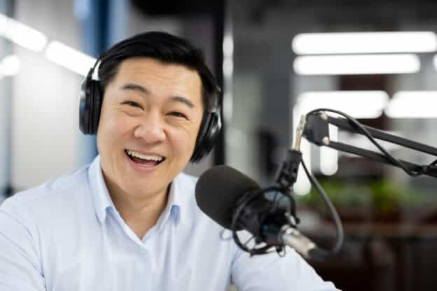 Professional podcast host smiling and speaking into microphone in studio