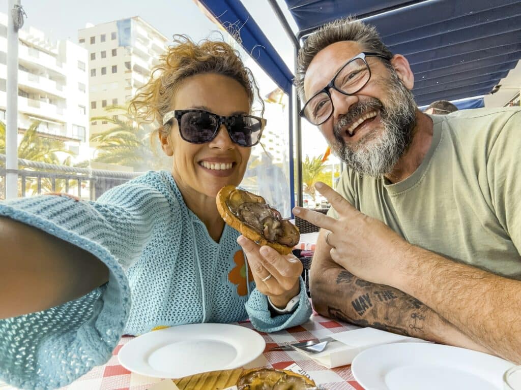 Smiling couple enjoying time at the restaurant, taking selfies and eating outside,