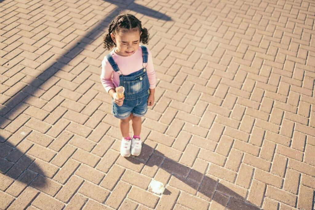 Crying kid drop ice cream on ground, floor and street in summer, sunshine and outdoors. Sad, unhapp